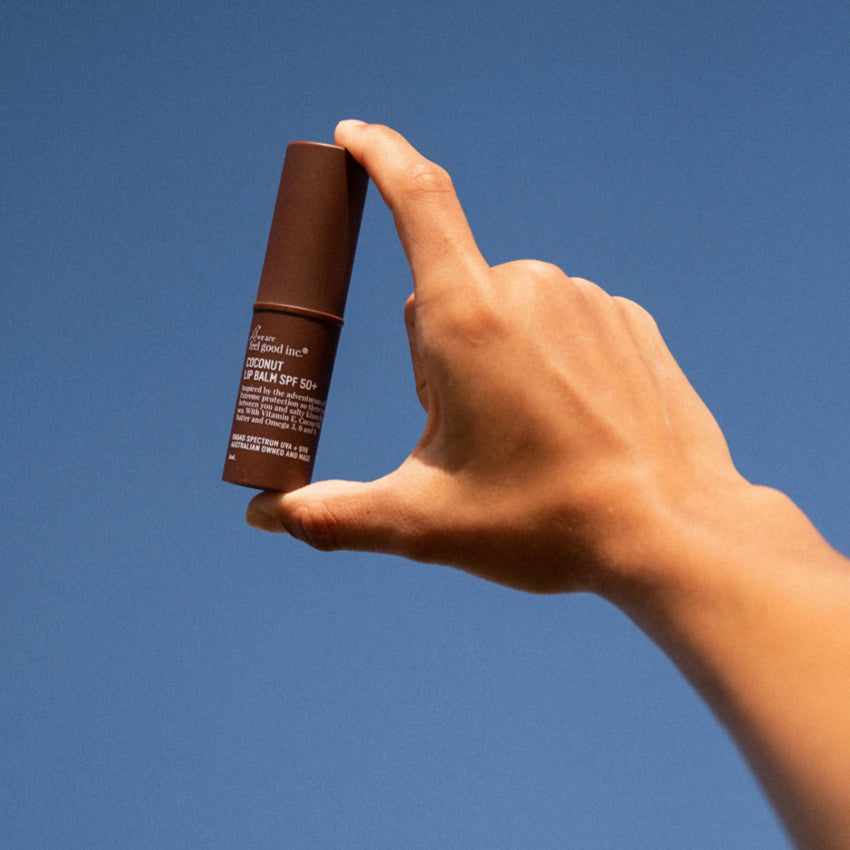 A hand holding up the We Are Feel Good Inc Coconut SPF 50+ Lip Balm to the sky