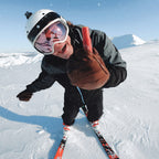 A skier holding the We Are Feel Good Inc Signature SPF50+ Lip Balm on a mountain