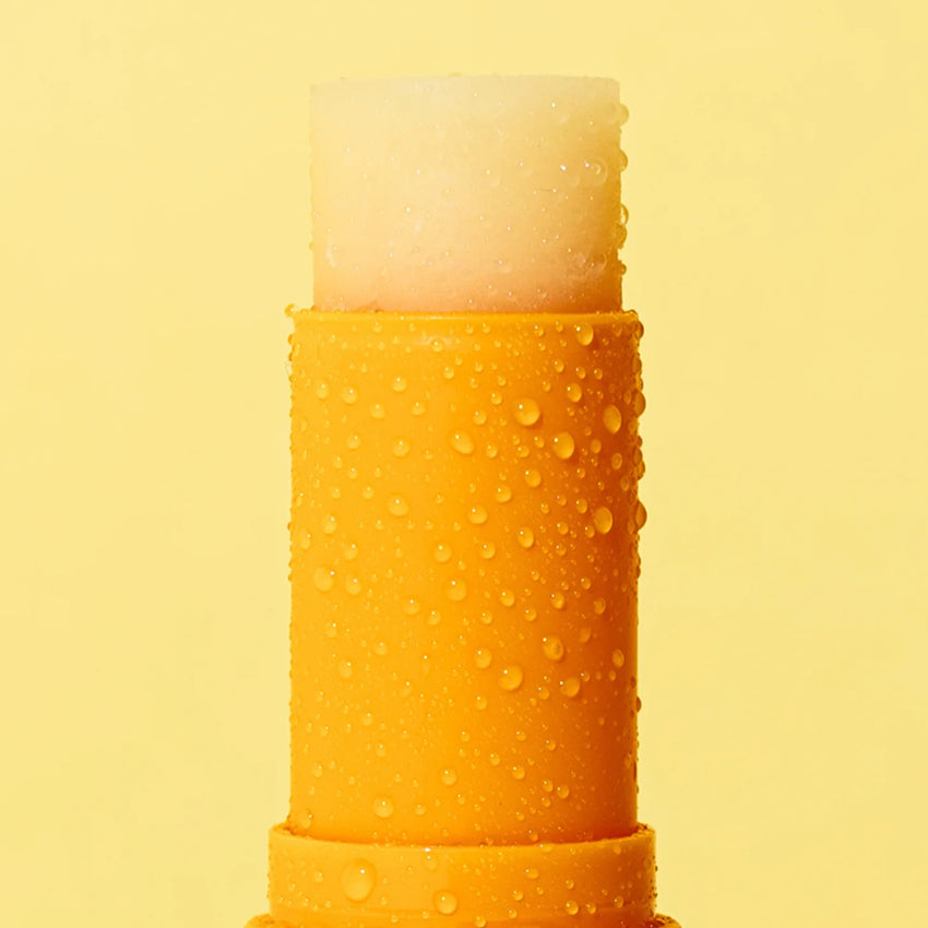 A close up of the We Are Feel Good Inc Tropical SPF50+ Lip Balm on a yellow background