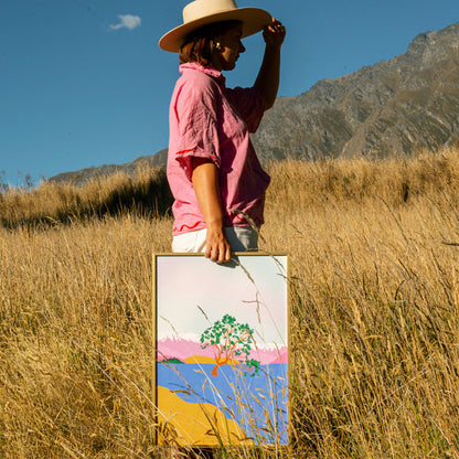 The West Moor Design Wanaka Tree Art Print with artist holding it in long grass