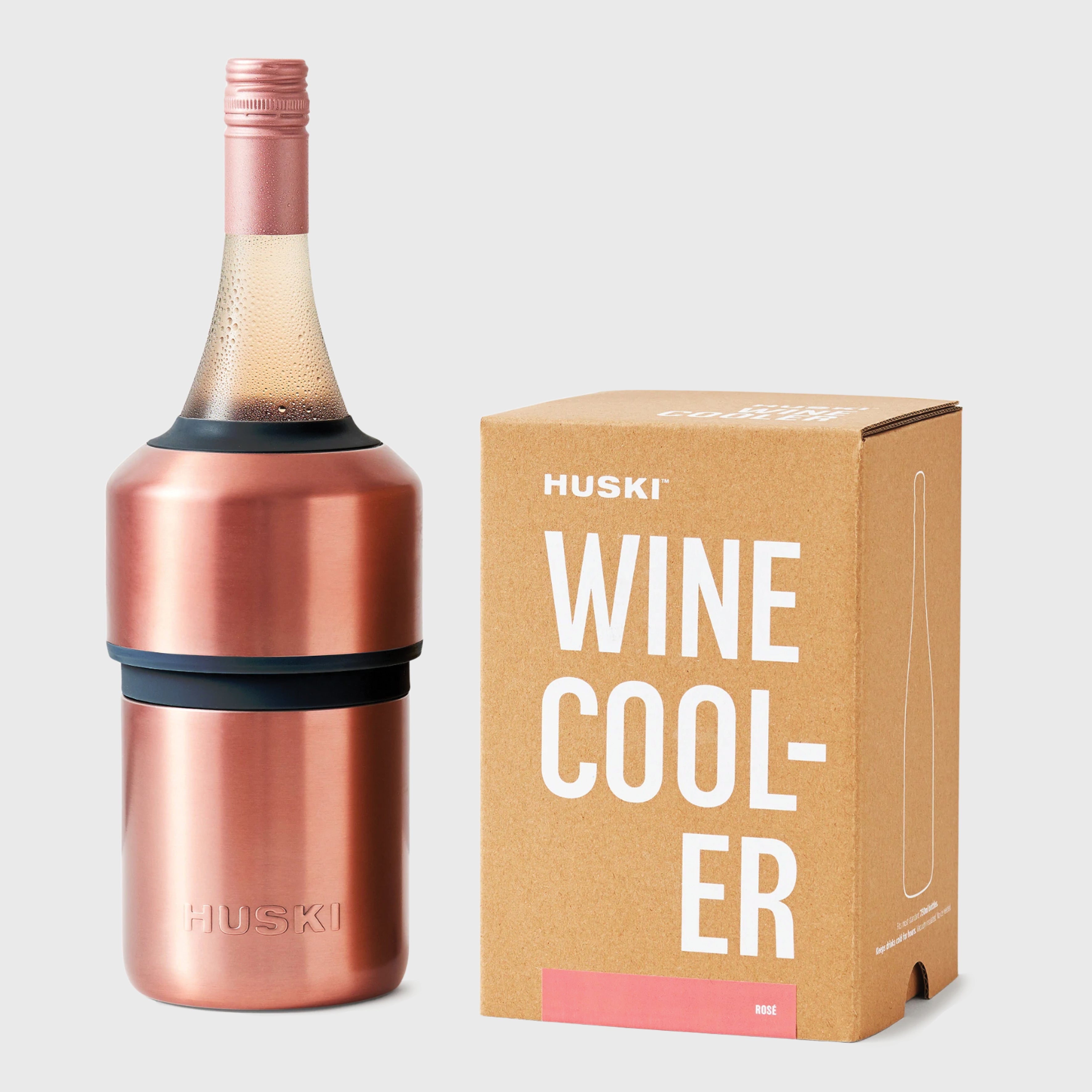 The Huski Wine Cooler in Rose with a wine bottle in it and next to its box on a blank background