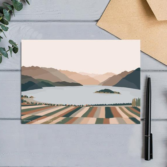 The Bridget Hall Designs gift card with a modern landscape design of Rippon Vineyard next to a pen and envelope.