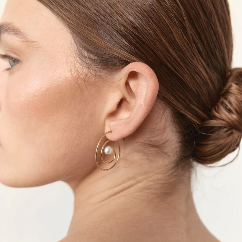 The Nina Gordon Swirl Spiral Earrings in Gold on a model