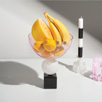 The Fazeek Geo Bowl in Pink with fruit in it alongside a fazeek candle, candleholder and wave glass
