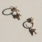 The Meadowlark Dove Signature Hoops in Gold Plated on a textured background.