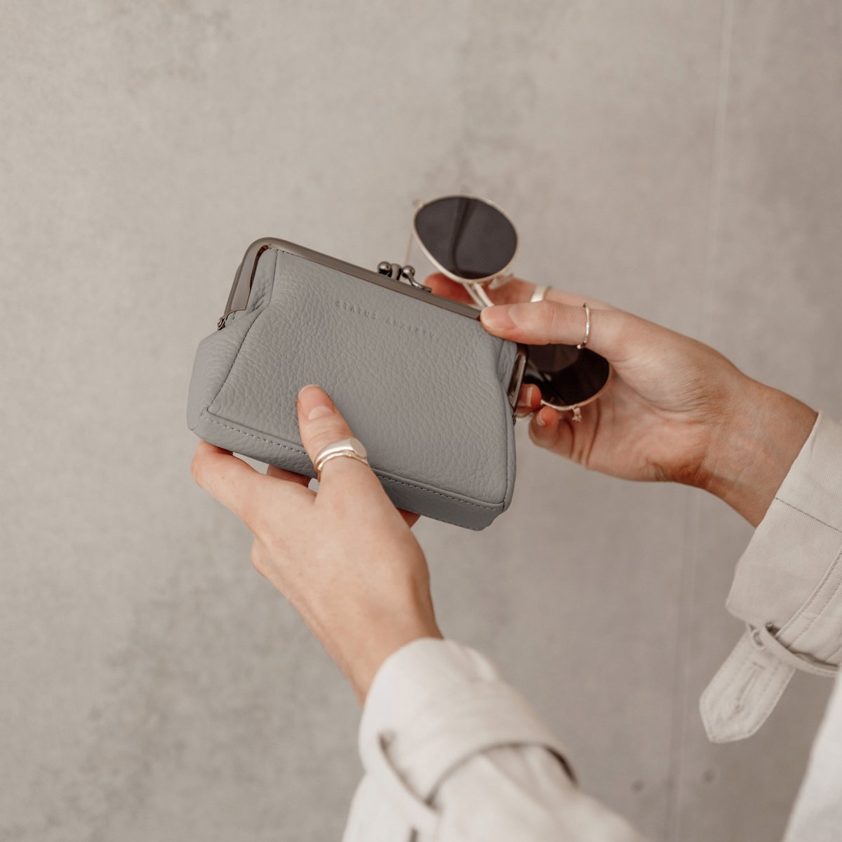 Status Anxiety Volatile Wallet in Light Grey in a persons hands