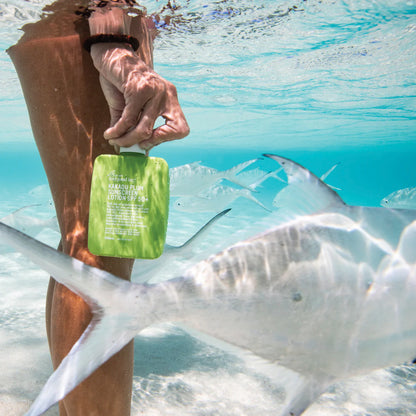 A model holding the We Are Feel Good Inc Kakadu Plum Sunscreen under the water with fish